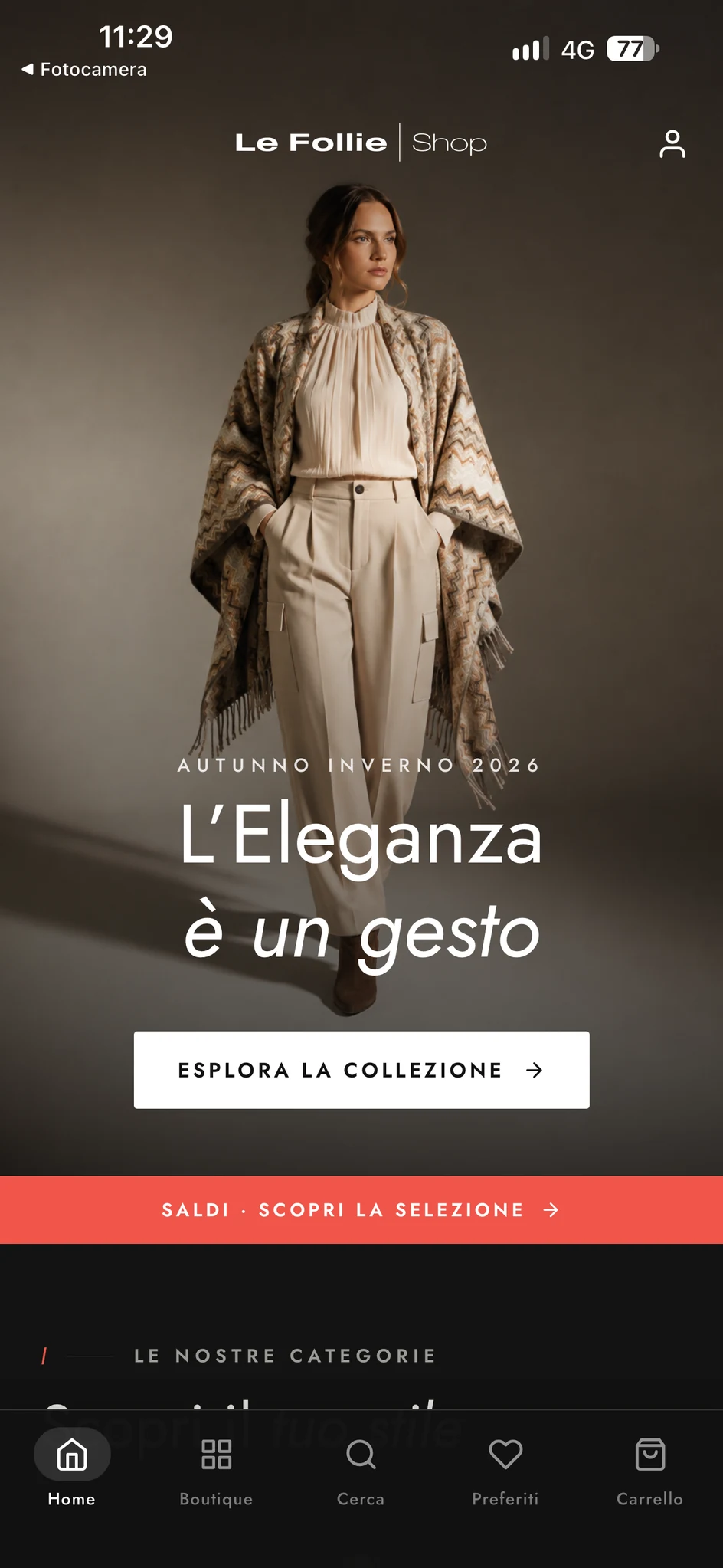 Schermata reale della home dell’app Le Follie Shop in modalità scura, con fotografia di campagna e navigazione inferiore; testi in italiano.