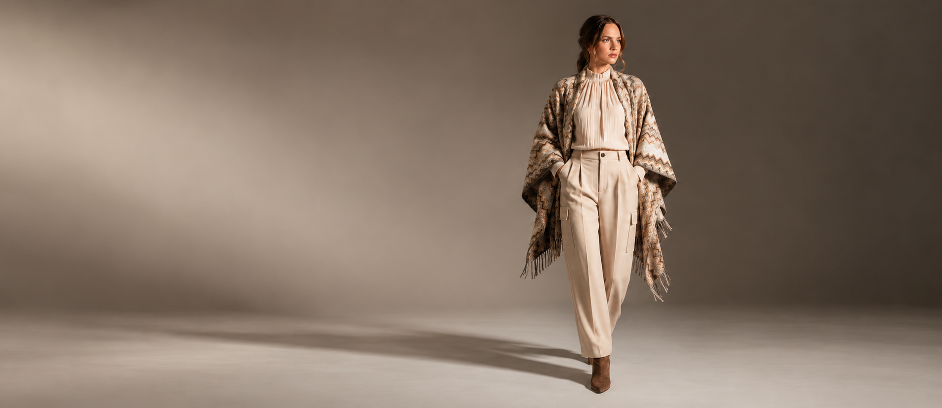 Blusa avorio, pantaloni sartoriali e mantella nei toni della terra